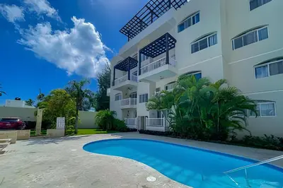 a villa with a swimming pool in front of a building at Beach Residence | Escapada Penthouse Vista Mar in Punta Cana