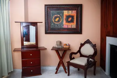 a room with a chair and a dresser and a mirror at Hotel Los Jardines in Santiago de los Caballeros