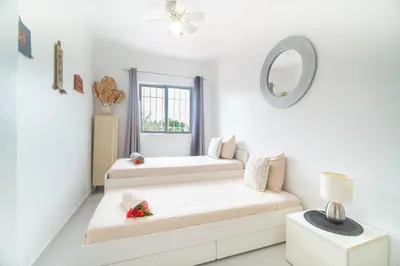 a white living room with two beds and a mirror at Villa Pauline in Bayahibe