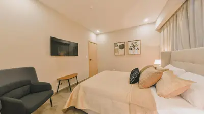 a bedroom with a bed and a chair and a television at Fully Serviced Apartment at Regatta Living II - 907 in Santo Domingo