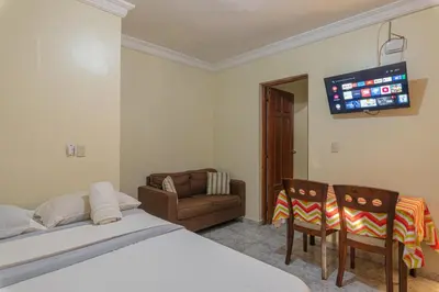 a bedroom with a bed and a couch and a tv at Tropical Island Aparthotel - Santo Domingo EsteRD in Santo Domingo