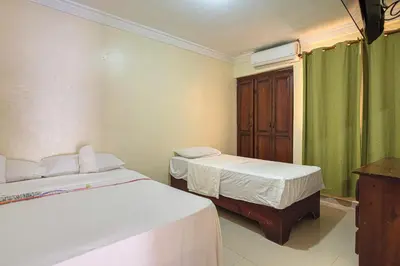 two beds in a room with green curtains at Tropical Island Aparthotel - Santo Domingo EsteRD in Santo Domingo