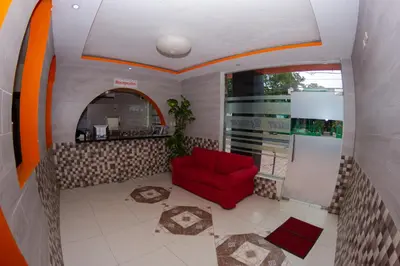 a living room with a red chair and a counter at Hotel Renacer in Santo Domingo