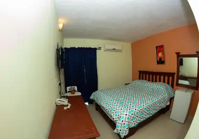 a bedroom with a bed and a desk with a phone at Hotel Renacer in Santo Domingo