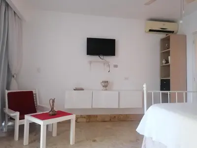 a white bedroom with a bed and a tv on the wall at Apartment Monocal in Boca Chica in Boca Chica