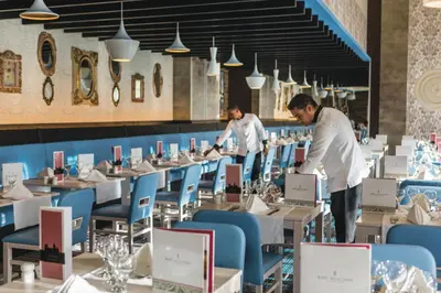 two chefs working in a restaurant with tables and chairs at Riu Republica - Adults Only - All Inclusive in Punta Cana