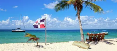 a flag on a beach with a chair and a palm tree at Private room in the Boca Chica Resort condominium in Boca Chica