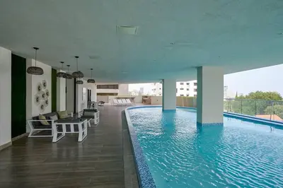 a swimming pool with chairs and a table in a building at Escape Apartments, Balcony, Pool, Gym & Spa in La Julia in Santo Domingo