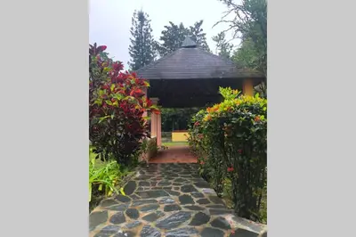 a walkway leading to a gazebo with flowers at Acogedora Casa Rural en plena naturaleza frente al Río con piscina Bonao in Bonao