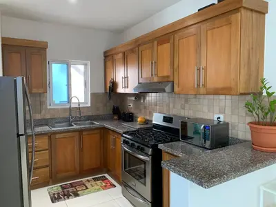 a kitchen with wooden cabinets and a stove top oven at Furnished Apartment - Residencial Olas - Gated Community - 24 hr Security in San Felipe de Puerto Plata