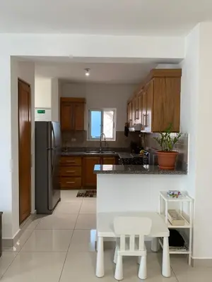 a kitchen with wooden cabinets and a white counter top at Furnished Apartment - Residencial Olas - Gated Community - 24 hr Security in San Felipe de Puerto Plata