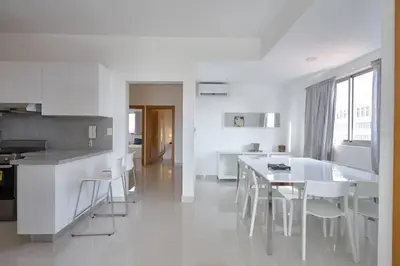 a white kitchen with a table and white chairs at Escape Apartments, Balcony, Pool & Gym in La Julia in Santo Domingo