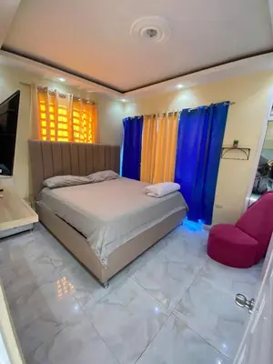 a bedroom with a bed and a chair and a television at Cozy Apartment RM in Santiago de los Caballeros