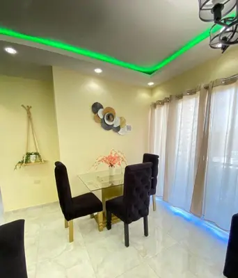 a dining room with a table and chairs with green lights at Cozy Apartment RM in Santiago de los Caballeros