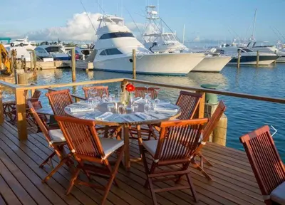 a table and chairs on a dock with boats in the water at Lux Villa Casa de Campo in La Romana