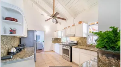 a kitchen with white cabinets and a ceiling fan at Lux Villa Casa de Campo in La Romana