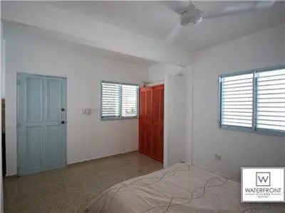 a bedroom with a bed and two windows at Bungalow #1 at Waterfront Playa Alicia in Sosúa