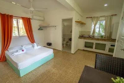 a bedroom with a white bed and a bathroom at Bungalow #8 at Waterfront Playa Alicia in Sosúa