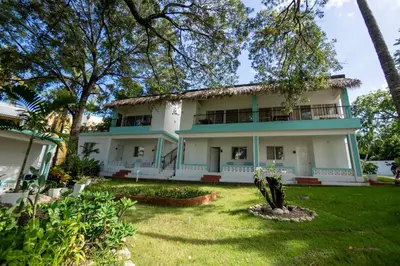 a large white house with trees in the yard at Room #24 at Waterfront Playa Alicia in Sosúa
