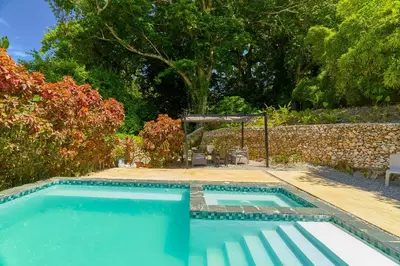a swimming pool in a yard with a stone wall at Casa Kafe in Cabrera