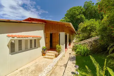 a small white house with a door and a yard at Casa Kafe in Cabrera