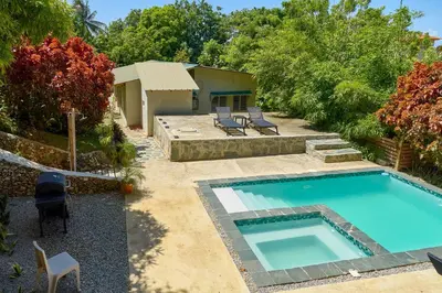 a swimming pool in a yard with two chairs and a house at Casa Kafe in Cabrera