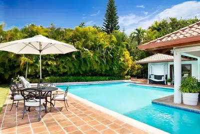 a patio with a table and umbrella next to a swimming pool at Los Lagos 19 - Sleeps 10 - Butler - Pool Hot Tub in La Romana