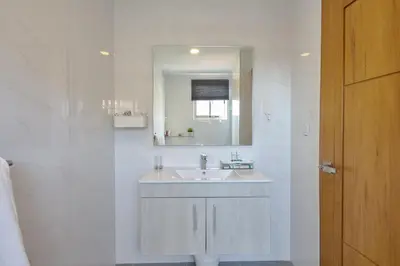 a white bathroom with a sink and a mirror at Apartments in La Julia 1 and 2 Bedrooms in Santo Domingo