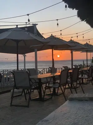 a group of tables and chairs with umbrellas on the beach at Bungalow #12 at Waterfront Playa Alicia in Sosúa
