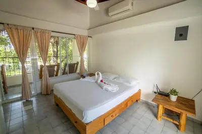 a bedroom with a bed and a table and windows at Bungalow #17 at Waterfront Playa Alicia in Sosúa