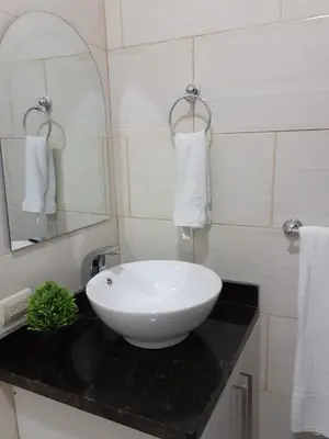 a bathroom with a white sink on a black counter at Apartment #21 at Waterfront Playa Alicia in Sosúa