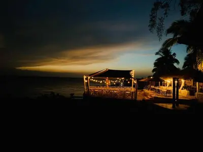 a building with lights on the beach at night at Bungalow #3 at Waterfront Playa Alicia in Sosúa