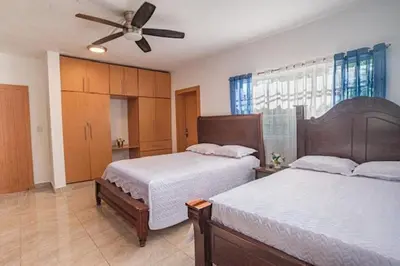 a bedroom with two beds and a ceiling fan at Villa Nilsa ( The Blue House ) in Baní