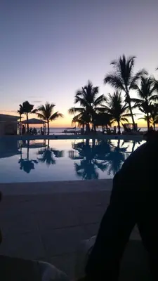 a view of a pool with palm trees at sunset at Estudio Frente al Mar Solo Adultos in La Laguna