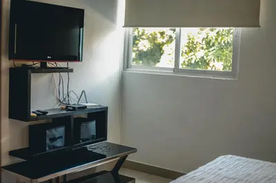 a room with a tv and a table with a television at ARMONIA 408 APARTMENT IN GAZCUE in Santo Domingo