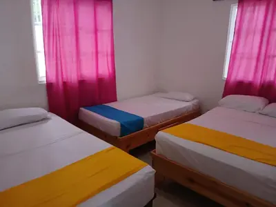 three beds in a room with pink and yellow curtains at Villa Boutique con Piscina Privada a Minutos del Aeropuerto SDQ in Boca Chica