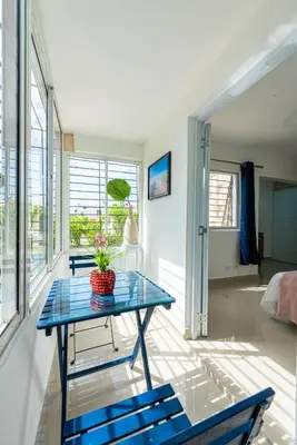 a room with a glass table and two blue chairs at Bamboo Hoouse in Santo Domingo