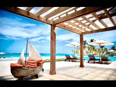 a hammock on a beach with chairs and umbrellas at Cana Rock Chic Golf de Lux in Punta Cana