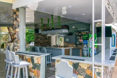 a bar with white chairs and a stone wall at Apartamentos in Condo Plaza Europa in Sosúa