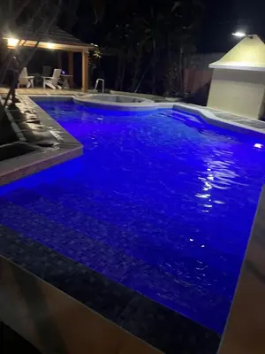 a swimming pool with blue water at night at Villa Luz in Baní