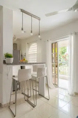 a white kitchen with a table and white chairs at Cozy 2 bdr condo, with pool area and free WIFI in Punta Cana