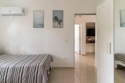 a white bedroom with a bed and a hallway at Cozy 2 bdr condo, with pool area and free WIFI in Punta Cana