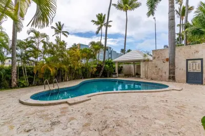 a swimming pool in a yard with palm trees at Cozy 2 bdr condo, with pool area and free WIFI in Punta Cana