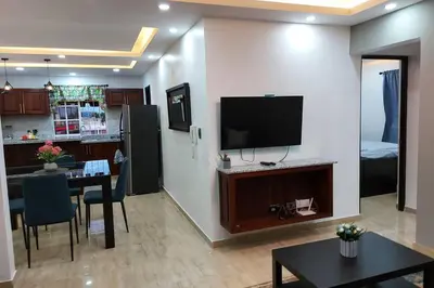 a living room with a table and a tv on a wall at Cómodo Apto de 2hab con Aire 2baños, cerca de todo en Alma Rosa I in El Seis