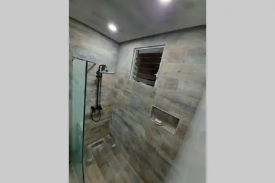 a bathroom with a shower with a stone wall at 4to nivel 2 habitaciones 2 baños Alma Rosa I in El Seis