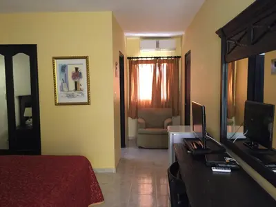 a bedroom with a bed and a tv and a mirror at Hotel Las Caobas in San Francisco de Macorís