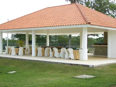 a gazebo with chairs and tables under it at Hotel Las Caobas in San Francisco de Macorís