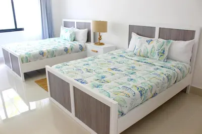 a white bedroom with two beds in a room at Amar'e Aparthotel & Spa in Las Terrenas
