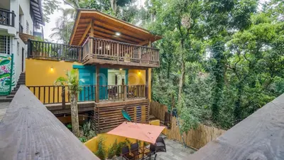 a house with a balcony and a table with an umbrella at El Yaguacil Aparta Hotel in Jarabacoa