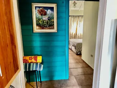 a hallway with a blue wall with a painting of a house at El Yaguacil Aparta Hotel in Jarabacoa
